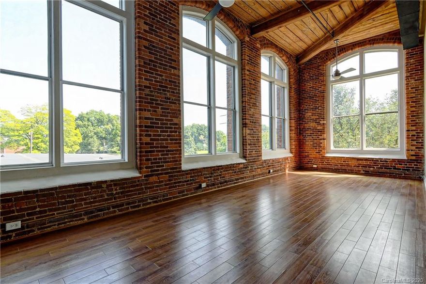 UNIQUE and CHARMING END UNIT with a view of uptown. Sophisticated urban living in the circa 1905 Historic Hoskins Cotton Mill. This second level corner unit impresses with 17' soaring wood ceilings, exposed brick and duct work, enormous exposed beams, 12' arched windows providing lots of natural light. 2 story bedrooms with 17' ceilings on main.  Modern kitchen w expresso cabinets and stainless steel appliances. Neat upstairs loft with double closet, perfect for bedroom or office/flex space. Washer and dryer hook-ups in the unit. View of uptown during  fall/winter months! No 2 units are alike. Secured building, 2 huge outdoor courtyards, elevator, laundry facility and eye catching multi-story open atrium. Brand new g-Geothermal HVAC unit. Unbelievable location minutes to Uptown, airport and Interstates.   **THIS HISTORICAL CONDO QUAILIFIES FOR A 50% TAX REDUCTION ON PROPERTY TAXES!!  Move-in ready. Well maintained unit being sold AS-IS.