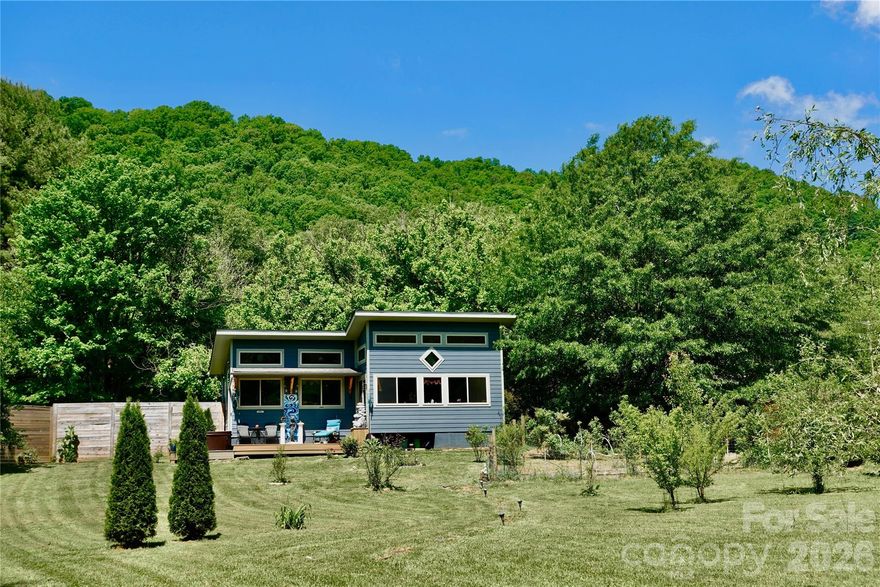 Peaceful Creekside Sanctuary with Blue Ridge Views & Separate Studio

Lovingly curated as a private park like retreat, this charming Barnardsville property offers the perfect blend of peaceful mountain living, natural beauty, and versatile space. Set at the base of Pinnacle Mountain on 1.18 mostly level acres with sweeping mountain views & creek frontage, the property feels far larger than its footprint, with distinct outdoor “zones” designed for gathering, gardening, relaxing and play. Walking distance to Big Ivy waterfalls, trails, and pristine creeks and an easy drive to both Weaverville and Asheville, this peaceful sanctuary offers the best of mountain living while remaining conveniently accessible to the amenities of town.

Highlights Include: 3BR/3BA, ~2,440 sq ft main home with warm hardwood floors, Spacious open-concept kitchen, living, and dining areas, Covered front & back porches + gas fireplace, Finished lower level with custom built-ins, storage & flexible living space, New roof in 2024, plumbing upgrades in 2025, deck painting & HVAC serviced 2026, New (2023) stunning ~600 sq ft detached studio/guest/work space with gorgeous views,  hot tub & sun deck
Extra large copper bath tub & granite / marble counters, Year-round creek frontage with peaceful meadow & fire pit/ sitting areas, Fenced organic garden, mature blueberry patch, orchard & perennial landscaping, Two sheds, 2-car carport & large driveway with room for RV/boat parking, Lovely established neighborhood with a peaceful, tucked-away feel on dead end road 1 mile from Big Ivy trails, waterfalls, and pristine creeks 30 minutes to Asheville and 15 minutes to Weaverville.

A rare opportunity to own a versatile and beautifully maintained mountain sanctuary with room to live, create, gather, and unwind.

Reach out to listing agent for listing video. Please no drive-bys.