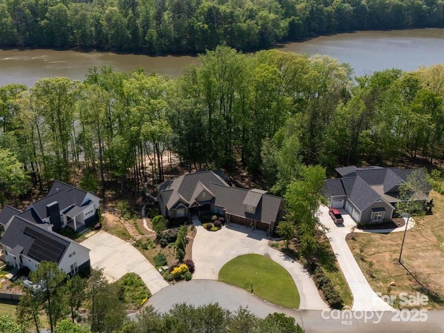 Luxury Lakefront Home on High Rock Lake. Discover unparalleled waterfront living in this stunning 5 Bedroom, 5 Bathroom home nestled in an exclusive gated community on High Rock Lake. Designed for comfort and entertaining, this home boasts an open concept floor plan with a large kitchen island perfect for hosting family and friends.  The finished basement offers a living area complete with a  2nd full kitchen and fireplace. Take in the breathtaking lake views from the covered porch or stroll down to your private pier, featuring a boat lift, 2 jet ski ramps, and 150' of sandy beach area for endless water fun. This immaculate home is situated on a beautifully landscaped .91 Acre lot situated in a cul-de-sac and offers privacy and serenity. The vibrant Community amenities include a clubhouse, pool, fitness center, pickleball courts and a playground, ensuring something for everyone. Start Living the Lake Life... It's a Lifestyle. Experience the best of lakefront living in this incredible home.