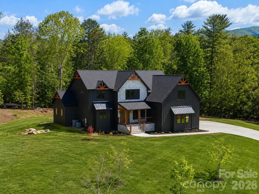 AVAILABLE MAY 2026 | NEW CONSTRUCTION

Ideally positioned just minutes from the charm, dining, and everyday conveniences of downtown Weaverville, and only 15 minutes from the cultural energy of downtown Asheville, this exceptional craftsman-inspired luxury mountain home is offered by the preferred builder in Garrison Hills, with a long-standing presence and commitment to the community. Thoughtfully designed, this residence offers refined craftsmanship, timeless architecture, and generous private outdoor living spaces, all with convenient access to I-26.

The home welcomes you with an open foyer, a classic staircase, and a dedicated main-level office with glass doors. The great room makes a dramatic impression with soaring 20-foot vaulted ceilings, oversized windows, and a stunning floor-to-ceiling stone gas fireplace. With 10-foot ceilings throughout the main living areas and 8-foot custom doors, the layout balances open living with well-defined, comfortable spaces.

Expansive sliding doors off the great room open to a screened rear porch with a wood-burning fireplace, creating a seamless indoor-outdoor living experience ideal for entertaining or quiet mountain evenings.

The chef’s kitchen is both elegant and functional, featuring rich natural gray wood-tone cabinetry, quartzite countertops, Thermador appliances, premium finishes, and a well-appointed butler’s pantry.

The main-level primary suite serves as a private retreat with glass door opening to exterior screened porch, dual walk-in closets, and a spa-inspired bath featuring a freestanding soaking tub and a walk-in shower clad in dramatic polished porcelain tile in warm brown tones.

Upstairs, a spacious sunlit loft offers the perfect setting for a cozy reading area or an open secondary office overlooking the great room. The upper level is complemented by a large bonus room—ideal for a playroom, workout space, or media room—and two generously sized ensuite bedrooms, each with luxurious private baths providing comfort and privacy for family or guests.

The thoughtfully designed garage with 13.5’ ft ceilings accommodates a flexible 2+1 configuration, for a three-car layout or an oversized two-car garage with extensive storage. Situated in the desirable luxury neighborhood of Garrison Hills, this private setting combines peaceful mountain living with everyday convenience—just minutes to I-26, grocery stores, shopping, dining, and the planned AdventHealth hospital.