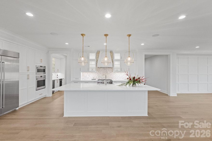 Just completed and move-in ready, this custom-built luxury residence in a brand-new upscale community showcases the highly sought-after Solana floorplan and is protected by a full builder warranty, plus pre-inspected for added peace of mind. From the moment you enter, elevated craftsmanship is undeniable. Wide-plank hardwoods, curated designer lighting, and extensive custom millwork, including grid accent walls and board-and-batten detailing, create a refined yet welcoming aesthetic. Designed for effortless living and elevated entertaining, the open-concept layout centers around a true chef’s kitchen featuring a Wolf gas range, Wolf wall ovens, Sub-Zero refrigerator, quartz countertops, custom soft-close cabinetry, and an oversized island made for gathering. A rare, fully equipped scullery adds exceptional function with an additional sink, ice maker, beverage refrigerator, and expanded prep and storage space, a luxury feature seldom found in new construction. The great room impresses with soaring ceilings and a gas-log fireplace, seamlessly flowing into the dining area for both intimate evenings and larger gatherings. The main-level primary suite is a private retreat with cathedral ceiling, seating alcove, and spa-inspired bath complete with jewel-box shower, rain head, dual vanities, and custom walk-in closets. Two additional main-level bedrooms with private en-suite baths provide ideal flexibility for guests or multigenerational living. Upstairs, a spacious recreation room with custom wet bar, sink, microwave, beverage refrigerator, quartz counters, and custom cabinetry, creates the perfect entertaining hub. Two versatile flex rooms offer endless possibilities, office, gym, media room, or hobby space, along with an additional en-suite bedroom and generous walk-in attic storage. Outdoor living is equally exceptional. The covered rear porch features a remote-controlled screen system, stone gas-log fireplace, and built-in heater for year-round enjoyment. Located just minutes from Birkdale Village, boutique shopping, dining, and scenic nature trails, this home delivers the rare combination of luxury finishes, thoughtful design, and prime location, without the wait of building.