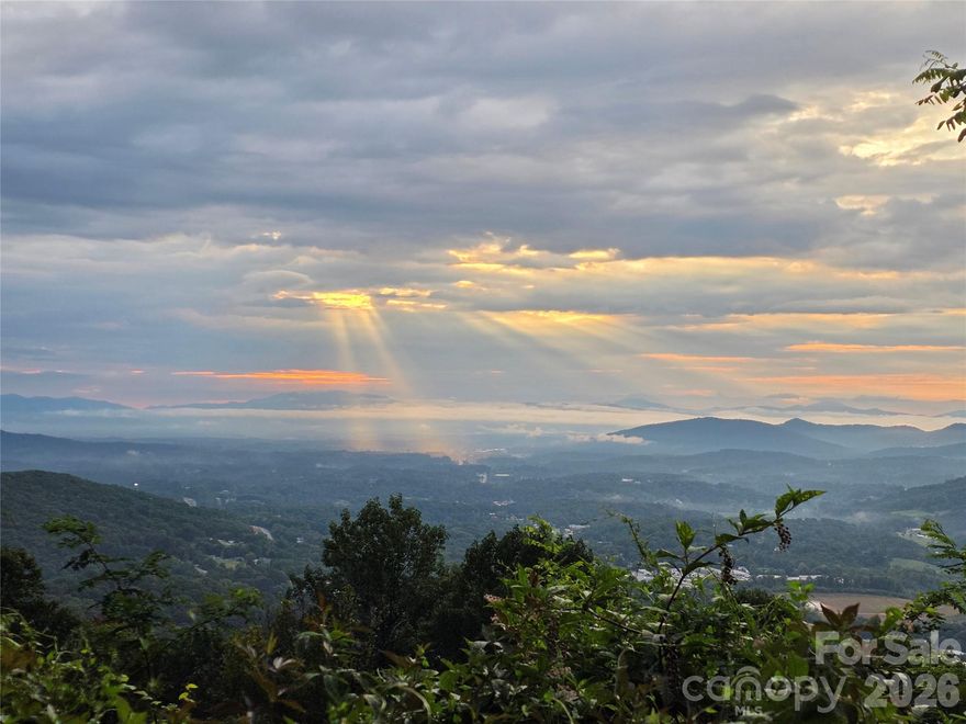 Stunning long-range east view lot in coveted WNC. Build the home of your dreams and awaken each morning to breathtaking vistas overlooking Biltmore lands in the distance. Enjoy the long-range layered views over Thompson and Pisgah Mountain as the lights twinkle through the night. Situated in the gated *Summit of Asheville* community, this exceptional lot enjoys underground power, fiber-optic internet, and neighborhood access to hiking trails, a seasonal waterfall, and a community garden where neighbors grow, gather, and connect. Paved roads provide effortless access directly to the property. Only 20 minutes from downtown Asheville and 25 from Waynesville, this property balances peaceful mountain seclusion with easy access to urban amenities. Wildlife is abundant and natural beauty surrounds the site. Don't miss your opportunity to see a one of a kind mountain view lot. Schedule a private showing now and secure your slice of mountain paradise with panoramic eastern and southern views!