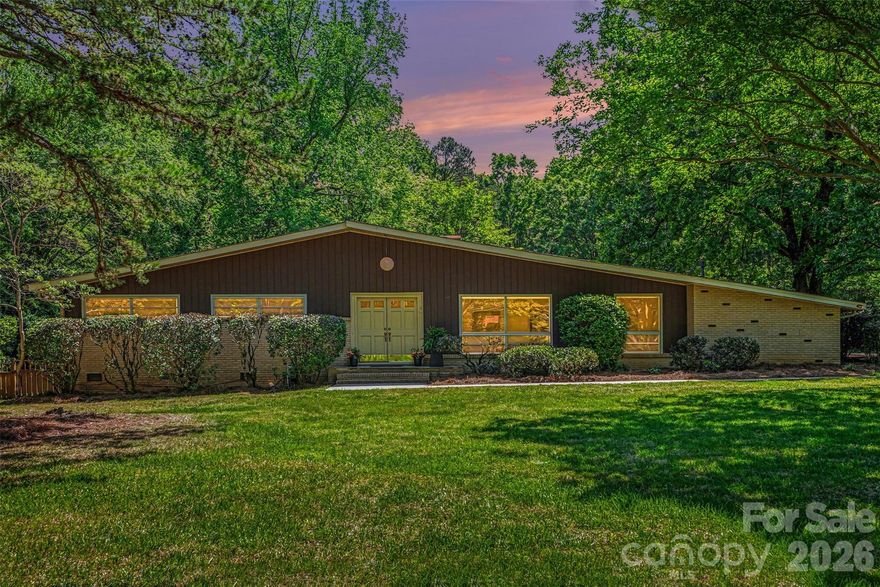 Discover this charming mid-century modern ranch on 1.3 acres in an unbeatable location. Tucked away in southeast Charlotte, this hidden gem offers the perfect mix of convenience, charm, and local favorites just minutes away.
A stunning wall of windows fills the home with natural light, creating a warm and inviting atmosphere throughout.
Step outside and unwind to the peaceful sounds of nature, or gather with friends and family in the spacious family room—complete with a built-in bar, perfect for entertaining. Floor-to-ceiling bookcases add character and make this space a true retreat for any book lover.
The entire interior has been freshly painted and features brand-new carpeting and luxury vinyl plank flooring, offering a clean, updated feel while leaving room for your personal touches.
Recent updates provide added peace of mind, including a new roof (2025), AC (2021), furnace (2023), and septic system pumped in February 2026. There is also the option to connect to sewer for future convenience. Outdoor shed/workshop fully wired with electricity—perfect for hobbies, storage, or a dedicated workspace.

This home is ready for its next owner to make it their own—welcome home!
