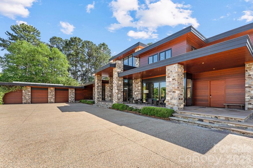 THE RANCH AT FAIRES RD: A Modern Equestrian Estate. Set quietly beyond the pace of Charlotte, this 75+ acre modern ranch estate offers a rare expression of architectural intention and landscape harmony. Conceived by Frank Smith after years of immersive study in contemporary design, and brought to life with interiors by Barrie Benson and craftsmanship by Kingswood Custom Homes, the home is both a personal retreat and a considered work of modern architecture.

The approach is deliberate—a sweeping motorcourt, anchored by a sculptural fountain, sets a tone of understated grandeur. Inside, the residence unfolds through volumes of glass and stone, where light becomes a defining material. Floor-to-ceiling storefront windows and pivoting glass doors dissolve the boundary between interior and landscape, opening to a composition of water, sky, and rolling acreage.

At the heart of the home, materials are both tactile and restrained—wide-plank black walnut floors, flamed leathered granite, and precision-crafted cabinetry that reveals itself at the touch. A curated Miele kitchen suite balances performance with quiet elegance, designed as much for gathering as for function.

The primary suite is conceived as a private pavilion, complete with a steam shower and an intimate outdoor bathing terrace—an experience that invites stillness and connection to the surrounding landscape.

Beyond the walls, the estate unfolds as an immersive environment. A heated pool with integrated current system allows for both leisure and training, while a private pond reflects the changing light of day. A driving range and par-3 golf introduce a distinct layer of recreation, thoughtfully integrated into the landscape.

The equestrian component is equally considered, designed to resonate with discerning equestrians and those drawn to a refined rural lifestyle. A well-appointed barn serves as both a functional working stable and a natural extension of the estate, offering four stalls, a dedicated tack room, and lofted hay storage for efficient daily operation. A covered equipment shed provides seamless access to vehicle storage and groundskeeping implements, supporting the stewardship of the land.

The surrounding acreage lends itself naturally to multiple fenced pastures and paddocks, allowing for thoughtful rotation, while rolling terrain and open sightlines create an ideal setting for private riding trails—suited for both leisurely rides and more focused training within the privacy of the estate. Enhancing the experience, the barn also incorporates a gym and a thoughtfully appointed kitchen and outdoor lounge space with fire pit, allowing for an effortless transition between training, care, and relaxation.

Integrated technology—via a Savant whole-home system—operates discreetly in the background, orchestrating lighting, climate, and security with precision. A Generac generator, underground propane reserves, and whole-home water filtration reinforce a sense of self-sufficiency.

An additional guest house, offered as-is, presents an opportunity for further personalization.

Located within convenient reach of Charlotte, yet intentionally removed from its immediacy, this estate offers a compelling duality: accessibility and escape. It is a place defined not only by its design, but by the experience it creates—quiet, expansive, and enduring.