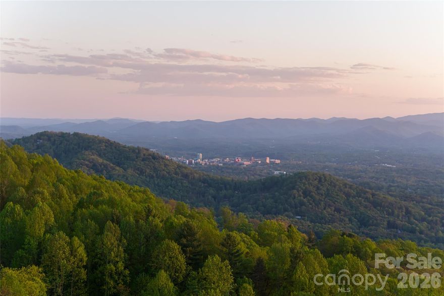 A rare opportunity to acquire a true legacy property defined by privacy, scale, and massive, long-range views of the Blue Ridge Mountains. Set along iconic Elk Mountain Scenic Highway at over 3,000 feet in elevation, this one-of-a-kind offering encompasses a vast, wooded landscape ideally suited for a private residential estate, generational compound, development, or select commercial endeavors. Natural ridgelines, soft knolls, mature hardwoods, and tranquil streams weave throughout the land, creating an immersive and secluded setting while remaining minutes from downtown Asheville’s celebrated dining, arts, and healthcare, as well as the Country Club of Asheville and the Blue Ridge Parkway. The topography lends itself to architecturally significant residences designed to capture sweeping mountain vistas and maximize privacy, with opportunities for private trails, outdoor living, and potential conservation easement benefits. In addition to the full parcel offered in this listing, the property is also available as two separately listed, smaller acreage tracts, providing flexibility for purchasers who may prefer to acquire a more tailored portion of the land. With its combination of expansive acreage, commanding mountain views, flowing streams, and exceptional proximity to Asheville’s most desirable amenities, this offering stands apart as a rare and enduring investment in Western North Carolina.