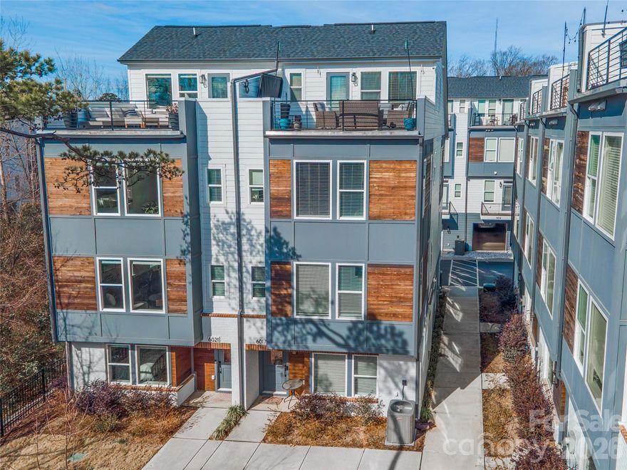 Welcome to 6017 Irwin's Branch Drive, where modern luxury meets unbeatable convenience.

Perfectly positioned just steps from local breweries, popular restaurants, and the nearby LYNX Blue Line, this stunning four-level townhouse offers the ultimate urban lifestyle with space to live, work, and entertain.

The entry level features a spacious side-by-side two-car garage, along with a private bedroom and full bath, ideal for guests, a home office, or multigenerational living.

Upstairs, the main living level is truly the heart of the home, filled with natural light and designed for gathering. The oversized kitchen island anchors the space, complemented by an open living and dining area and a private terrace?perfect for morning coffee or evening unwinding.

The third level offers a luxurious retreat with a large primary suite, complete with a spa-inspired bath and generous closet space. A second spacious bedroom with its own en suite bath provides comfort and privacy for family or guests.

The fourth level is incredibly versatile, featuring a full bath and flexible living area that can serve as a fourth bedroom, office, fitness studio, or creative space. This level opens to the show-stopping rooftop terrace, an incredible outdoor oasis overlooking a serene, tree-lined setting. Whether entertaining friends or enjoying a quiet sunset, this space delivers a rare blend of privacy and city living.

This is urban townhome living at its finest! Space, style, and a location that simply can't be beat.