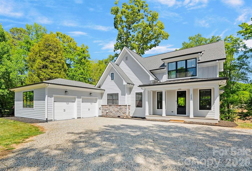 Experience the perfect blend of modern edge and lakefront lifestyle at 1420 Roundstone Road. This 2019 custom-built masterpiece sits on a sprawling 1.14-acre lot with no HOA, offering a rare sense of freedom on the shores of Lake Norman. From the moment you pull up the expansive U-shaped driveway, the home’s cool, contemporary vibe is undeniable. Inside, the open-concept living area features stunning solid hardwood floors and soaring floor-to-ceiling glass sliders that frame far-reaching water views. The chef-inspired kitchen is a true centerpiece, with custom soft-close cabinetry, sleek quartz countertops, a decorative range hood over the gas range, and premium Frigidaire Gallery appliances. Whether you’re prepping at the coffee station or cleaning up in the farmhouse sink that overlooks the lake, the design is as functional as it is beautiful.
The primary suite serves as a sanctuary with massive windows and a custom walk-in closet. The attached ensuite is a showstopper, featuring a large vanity with dual sinks and a sleek zero-entry shower. Practicality meets luxury throughout the home with a dedicated dog-washing station for your furry friends, a quiet small office tucked off the kitchen, and a walk-in pantry for ultimate storage. For total peace of mind, the property is equipped with a whole-home Generac generator, an approximately 900 sq ft epoxied floor garage, a water softener system, and walk-in attic that handles all your storage needs with ease.  Outdoor living is where this property continues to shine. Step out onto the covered back deck, finished with durable Trex flooring, to enjoy the breeze or head down to the water’s edge. The covered boathouse is equipped with electricity, storage closets, two boat slips—one featuring a newer lift—and two jet ski ramp floats. The dock area was recently dredged by Lancaster Custom Docks.  Whether you’re looking for high-energy lake recreation or a spot to relax in the lakeside sitting area, this spectacular home delivers the ultimate Lake Norman lifestyle.