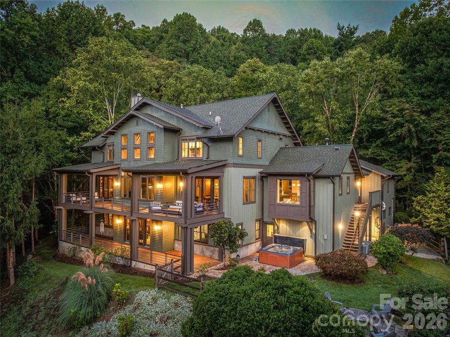 Experience refined mountain living in this 6,000 SF contemporary estate on 5.5 private acres in the sought-after Oxbow Crossing community just 20 minutes from Downtown Asheville. The home features soaring ceilings, walls of glass, custom-designed metalwork, and panoramic mountain views. Thoughtfully planned, the house is both elevator-ready and offers flexibility for a main-floor primary suite.

The main floor features a showpiece chef’s kitchen with Gaggenau double ovens and range, Sub-Zero refrigerator, EarthStone wood-burning pizza oven, Miele coffee station, custom cabinetry, soapstone and stainless steel countertops, and a very spacious walk-in pantry. The living and dining areas open to a covered deck ideal for al fresco gatherings. A media room, generous office space, powder room, and a large en suite bedroom finish off the main level. The office and large ensuite bedroom offer the flexibility to be combined into a main-floor primary suite.

Upstairs, the open hallway overlooks the living room with grand mountain views. The primary suite offers a spa-inspired bath, soaking tub, walk-in shower, double vanities, and custom closet, joined by two additional large ensuite bedrooms a sitting room/craft room or office and a full laundry room.

The daylight lower level includes a second large living area, a guest suite with a full bathroom and storage, a family/billiards room, a large custom bar, a gym, and an oversized woodshop.

Smart systems include Gigabit Ethernet, three-zone HVAC, dual tankless water heaters, propane heat, a whole-house generator, and an EV-ready two-car garage. Located just minutes from downtown Weaverville and the Blue Ridge Parkway, this exceptional estate blends privacy, sophistication, and modern mountain design.
