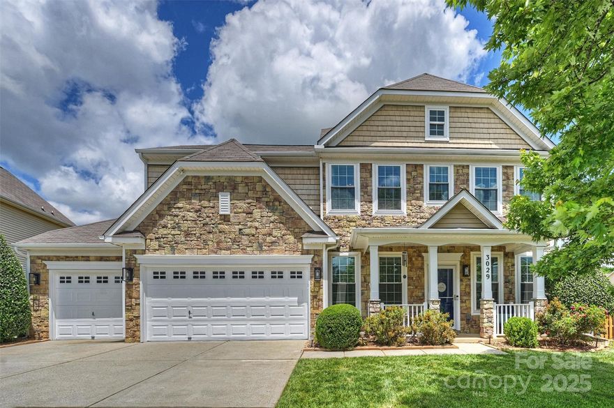 Stately home that has been meticulously maintained with stone accents and rocking chair front porch offering custom features in fabulous location close to Charlotte! Enjoy wood laminate floors on the main level, incredible open kitchen with island, stainless appliances, sunny dining nook and family room with built-in shelves and gas fireplace.  Guest suite and full bath on the main level, drop zone, abundant storage, living room and dining room offer lots of flexibility!  The upper level features four bedrooms including a stunning primary suite with oversized bathroom and walk in closet.  Newer carpet, large laundry room and secondary bedrooms and hall bath complete the upper level.  Many opportunities for outdoor enjoyment include screened porch with built-in table, extended patio and driveway, privacy fence, shed, playhouse and community pool! Three car garage w/ EV charger, and freshly painted exterior complete this fine home! Newer HVAC, all appliances remain, close to everything!