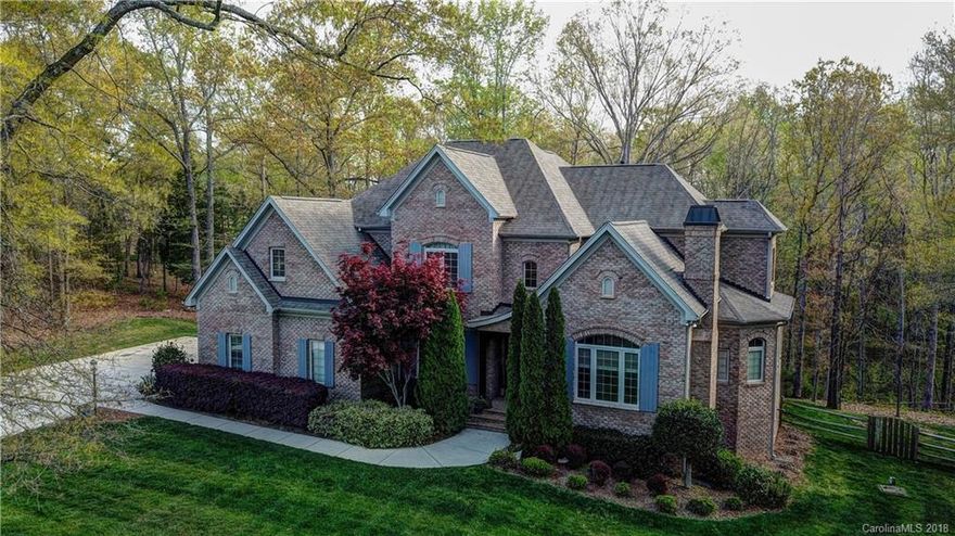 Custom built, luxury estate is located in Indian Land, just outside of Waxhaw, approximately 15 minutes from Ballantyne. From the exquisite masonry on the exterior, to the herringbone designs carried into the hardwoods in the foyer, luxury & craftsmanship abound. Every bathroom is a feast for the eyes, w/high end finishes & custom cabinetry and millwork everywhere. Master on main w/sitting room. Exquisite office w/coffered ceilings & fireplace. Elegant dining room off two story foyer. Stacked stone fireplace at the heart of the home w/custom built ins. Kitchen boasts subzero fridge, pot filler above gourmet gas cooktop, apron sink w/hidden dishwasher, & custom coffee bar. Exterior boasts custom patio designed for entertaining--grilling station, a huge covered porch, pergola, & great views of the forest. Evenings on this patio are magical w/ambient lighting. Upper level theater room & generous sized bedrooms & baths. You can't build for this remarkable price.