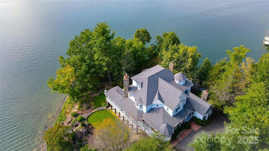 Perched on its own private peninsula with over 550 feet of shoreline, this custom Lake James waterfront estate captures panoramic views of the lake and surrounding mountains. A tranquil retreat, it features four unique water elements, including a cascading waterfall flowing through lush, tropical landscaping into the deep, clear waters below. The nearly 7,000 sq ft Victorian home spans three levels and boasts a generous wraparound porch perfect for entertaining and sunset watching. Inside, a grand foyer welcomes you with soaring ceilings and a curved staircase. The two-story circular library is a rare architectural gem, while the remodeled kitchen with a wood-burning fireplace creates a cozy gathering space. The second-floor primary suite includes a private balcony and a spa-inspired bath. Additional bedrooms, flexible living spaces, and a finished basement offer room to relax or host. Park your boat under the brand new dock, relax under the stars by the fire pit on the point, and enjoy the best parts of lake living. **Owner Financing being offered at 3.125%!