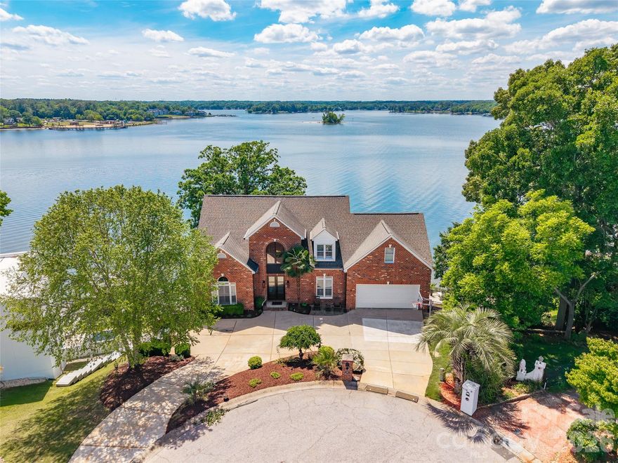 Stunning waterfront retreat on Lake Wylie offering breathtaking main channel views and unforgettable sunsets from nearly every room. Located in Tega Cay, this exceptional 4 bedroom, 3.5 bath home is designed for luxurious lakefront living with panoramic water views greeting you the moment you walk through the front door.
Inside, you’ll find gorgeous architectural details throughout including shiplap walls, vaulted ceilings, beautiful wood ceiling accents, and two impressive stone gas log fireplaces located in the great room and primary suite. The spacious main-level primary suite features a luxury bath and an incredible walk-in closet/dressing room.
Designed for entertaining, the home also includes a bunk room, rec room with kitchenette, and a stunning stone-trimmed bar area. Expansive covered porches and a private balcony provide the perfect place to unwind while taking in the long-range lake views.
Step outside to your own private waterfront oasis featuring a lakeside saltwater pool and spa, covered dock with boat lift, and direct access to the main channel for boating and water recreation. Additional features include a double attached garage, walk-in attic storage, and exceptional indoor and outdoor living spaces that make this lake home truly one of a kind.