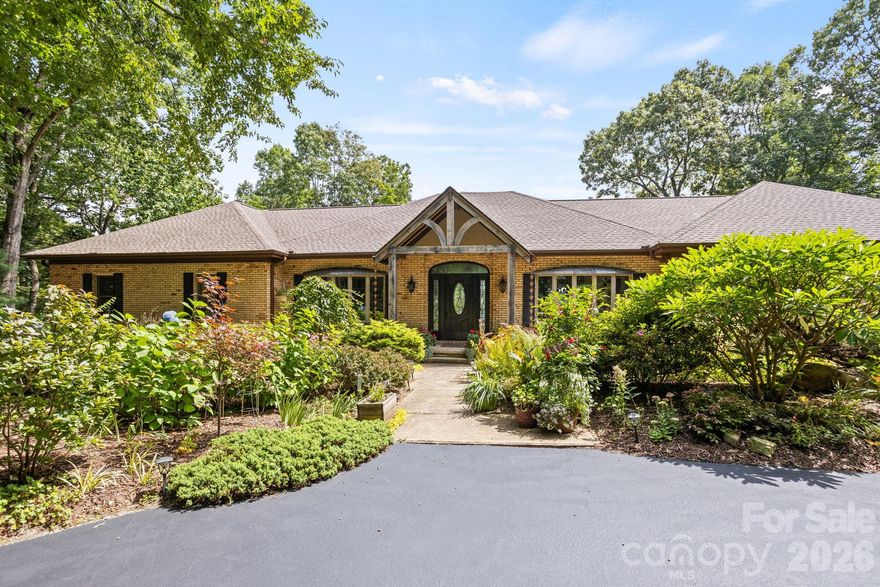 Absolutely stunning and complete transformation and renovation, this exceptional home with mountain views is privately tucked away on over 2 acres of meticulously landscaped grounds in the prestigious gated community of Kenmure. A true gardeners’s paradise, this property features meandering pebble pathways, a serene garden patio and lush, mature landscaping offering privacy, beauty and tranquility. Step inside to discover an amazing open concept and main level showcasing a gourmet chef’s kitchen with high-end stainless steel appliances, an oversized island with prep sink and breakfast bar, pantry, an abundance of cabinetry and counter space for all your culinary adventures. The kitchen opens into a sunlit breakfast room, open dining area and an impressive great room centered around a striking floor to ceiling unique gas fireplace. The huge primary suite is a private retreat featuring plantation shutters, designer walk-in closet and a luxurious spa-like bath with dual vanities, a unique walk-in waterfall shower and soaking tub. Also on the main level is a guest bedroom and guest bath, a powder room, stunning den/TV room, office/studio and well appointed laundry room with sink and cabinetry. The lower level offers a generous family/game room and huge guest suite with ensuite bath. You will also find ample unfinished storage space for all your needs. Whether you are entertaining on the large screened porch, relaxing on the open deck or enjoying the peaceful garden patio, every corner of this home is designed to embrace the best of luxury mountain living.