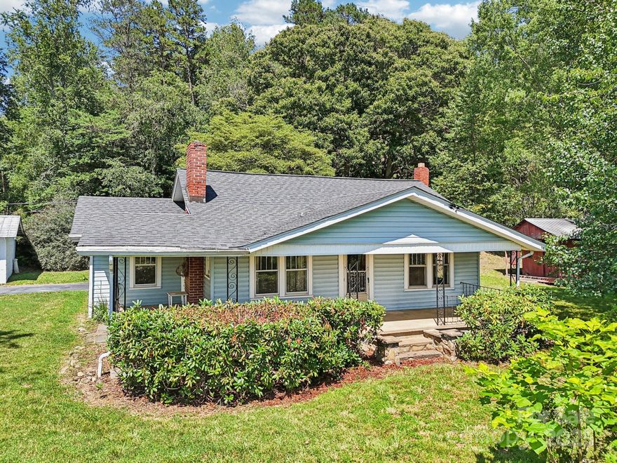 Back on the market at no fault of the seller! Perched at the end of a private drive on 3.4 scenic acres, this 1930s three-bedroom, one-bath cottage offers vintage charm, seclusion, and mountain views. Enjoy long-range vistas from the wrap-around porch—perfect for morning coffee or evening sunsets. Inside, abundant windows fill the home with light. A red brick fireplace centers the living room, while a second wood stove adds charm. The layout includes a flex/laundry room with exterior access for added convenience. Mature trees and rhododendrons frame the stone walkway to the front porch. The oversized one-car garage suits a workshop or studio, and a red barn-style outbuilding offers storage or project potential. Just 8 minutes to Westridge Market, retail, and dining, with easy access to Pisgah View State Park and under 30 minutes to downtown Asheville. Whether you're looking to downsize, invest, or enjoy a peaceful full-time residence, this home is full of possibilities.