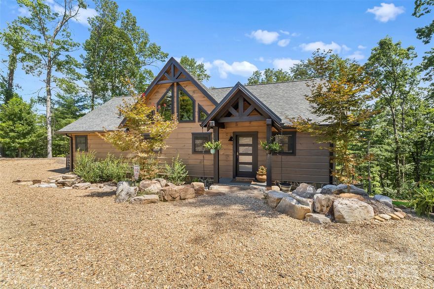 Nestled on 1.41 acres between 2 conservation areas, this stunning Blue Ridge log home offers a tranquil mountain escape with breathtaking lake views.  Enter the home across the rock bridge surrounded by boulders and a wet weather rock bed. The main level welcomes you with a spacious, open great room that shares a cozy two-sided gas fireplace with the adjacent covered porch and has lake views surrounded by the trees. The primary suite is conveniently located on the main floor and has private balcony providing lake views and a peaceful sanctuary. An additional bedroom with ensuite full bath are also on this level, perfect for guests. Guest bath and laundry on main level as well. The lower level is designed for both relaxation and entertaining. It features two more bedrooms, a full hall bathroom and a dedicated office space for remote work. The large great room on this floor is an entertainment hub, complete with a wet bar for serving drinks to family and friends. Tin ceiling, stained concrete floor and wine nook under stairs. Retractable glass sliding doors let you enjoy the lake views. The deeded community boat slip is just a short walk or golf cart ride away for easy access to Lake James. As a resident, you'll also enjoy membership to Camp Lake James, offering an array of exclusive amenities and social events. This home is more than a residence; it's a lifestyle, blending rustic charm with modern comfort  & lake views with endless opportunities for recreation on one of North Carolina's most beautiful lakes.