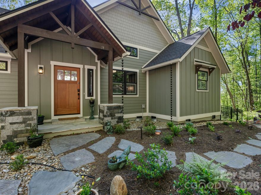 Tucked quietly into a private corner of The Boulders, one of Hendersonville’s most sought-after gated communities, this 2024 custom Craftsman residence offers something increasingly rare: true privacy, intentional design, and a lifestyle that feels both elevated and effortless. Positioned on a premier corner lot and wrapped in thoughtfully curated landscaping, the property creates a sense of arrival that is both peaceful and refined. Every stone, every path, every planting has been deliberately and situated to capture the mountain views, resulting in a setting that feels more like a personal retreat than a neighborhood home.


From the moment you step inside, the craftsmanship becomes evident. Warm L & M Timberline engineered wood flooring grounds the space, while custom built-ins and plantation shutters add a level of finish that speaks to both quality and care. Natural light pours through expansive sliding glass doors, framing serene views of surrounding greenery and inviting the outdoors in. The layout flows seamlessly, designed for both quiet mornings and meaningful gatherings.


At the heart of the home, the kitchen is as functional as it is beautiful. Anchored by an induction cooktop, stainless statement hood, and double ovens, it is complemented by an oversized walk-in pantry and an inviting eat-in dining space. Just beyond, a screened-in porch extends the living area, offering a peaceful place to enjoy summer evenings in comfort, surrounded by the gentle sounds of nature.

The home has been thoughtfully designed to accommodate a wide range of lifestyles. A built-in pet bathing station in the mudroom adds both charm and practicality, while an ADA-compliant ramp provides easy access to the backyard. Whether for pets, guests, or multigenerational living, the home adapts with ease.


The outdoor living experience is where this property truly distinguishes itself. Trex decking to a winding rock path leads you through lush landscaping to a beautifully designed flagstone fire pit, where evenings can be spent under the stars. A vibrant rose garden adds color, fragrance, and a sense of timeless romance, offering a daily reminder to slow down and savor the moment.


The primary suite is a private sanctuary, thoughtfully designed to deliver both luxury and comfort. Its spa-inspired bath is finished with porcelain Daltile and features a beautifully appointed shower experience with multiple water sources, including a rain head, wall-mounted shower head, and handheld fixture, creating a truly indulgent daily retreat. A garden tub with a heated back offers the perfect place to unwind. Throughout the home, custom closet systems add a refined sense of organization, seamlessly marrying function with elegance.


One of the most unique and valuable features of this property is the oversized garage configuration. In addition to a standard two-car setup, one bay has been purposefully built to accommodate a camper van or RV, complete with a 12-foot-high door and dimensions of approximately 30 feet deep by 12.5 feet wide. The garage flooring has been upgraded for durability, making this a rare and highly functional asset for those with adventure in mind.


Additional features include porcelain tile accents, barn door entries, whole-house generator wiring for peace of mind, and a level of finish that reflects careful attention to every detail.


Located just minutes from the charm and convenience of downtown Hendersonville, The Boulders offers a gated, active community setting while still allowing this home to feel tucked away in its own private enclave. It is a place where luxury meets livability, where thoughtful design enhances daily life, and where every detail has been considered.


This is more than a home. It is a retreat, a refuge, and a place to truly live well. Minutes from downtown Hendersonville, Asheville airport, Sierra Nevada Mills River campus, and premier health care a Pardee medical center.