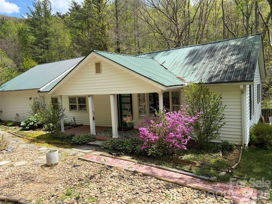 PRICE REDUCED – OWNER SAYS SELL! All offers will be submitted for approval.

Welcome to a true nature lover’s paradise in the sought-after community of Celo. This charming home is surrounded by lush gardens and offers a peaceful setting with beautiful views of the forest and creek.

Inside, a spacious living room opens seamlessly into a music room, creating a warm and inviting flow that continues into the kitchen and bright sunroom—perfect for relaxing while enjoying the natural surroundings.

The home features 2 bedrooms and 2 updated bathrooms, with abundant closet space and storage throughout. The large primary suite includes a cozy sitting area and a walk-in closet. The second bedroom offers privacy with its own full bath and generous closet.

Additional highlights include:

New laminate flooring
Oversized 2-car garage with extra space for a studio or workshop
Beautifully landscaped front gardens and a serene patio garden in the back
A charming new footbridge over Clear Creek, leading to a tranquil retreat area

Ideally located near outdoor and cultural destinations including the Toe River, Mount Mitchell, the Appalachian Trail, Penland School of Crafts, and local observatories and planetariums. Convenient to Burnsville, Spruce Pine, Marion, Asheville, and Boone.

Don’t miss this unique opportunity to own a peaceful mountain retreat!