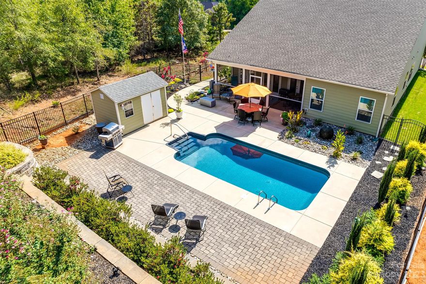 Resort style living awaits you at this better than new home, which boasts a stunning 24' pool surrounded by lush landscaping! Take in lake views from the rocking chair front porch, & then head inside to this open & light filled floor plan. The great room w/ it's coffered ceiling welcomes you to the chef style kitchen - w/ a gas cooktop, quartzite counters, expansive island, & ample cabinets & storage! The entertaining space continues to a generous screen porch, & when you're not relaxing by the pool, there is extended yard space to garden. The primary bedroom features dual closets, & there is a flex room w/ french doors. Other features include a large storage shed, retaining wall added for additional usable yard, aluminum fencing, custom draperies, impressive laundry room, & more! Refrigerator, washer, and dryer remain w/ the home. Edgewater is a destination community w/ amenities galore, incl golf, paddlesport launch, sport courts, clubhouse, community activities, & the list goes on!