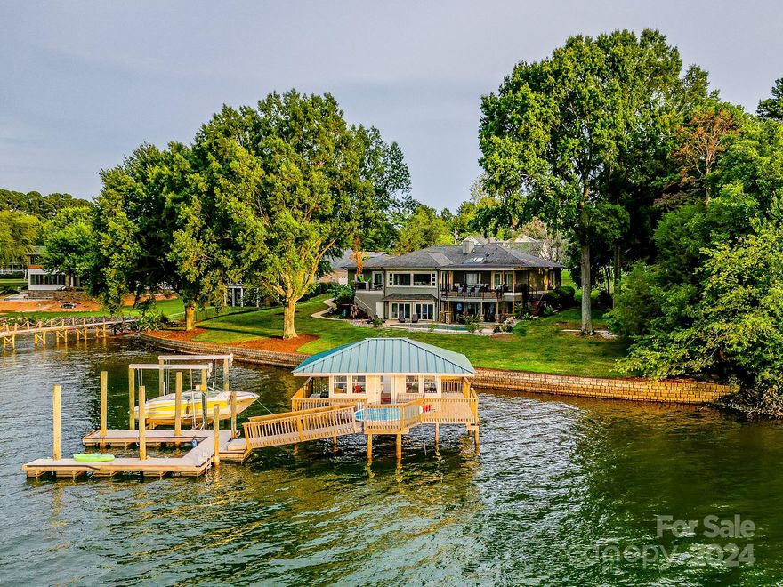 Waterfront paradise on Langtree Peninsula! Expansive Water Views, heated salt-water Pool and Spa, Boathouse, deep-water Dock with lift, outdoor Fireplace, Firepit, Basement Recreation space, and Theater. Renovated in 2023 featuring an open floorplan with walls of windows inviting panoramic Lake Norman Views. On the main level a Stone Fireplace wall with built-ins anchors an enormous Great Room. The adjoining Kitchen features two islands and opens to a grilling deck. The Waterside Dining Room and oversized Owner’s Suite open to a large Covered Porch. The Owner’s Bath is a show-stopper with spa shower and freestanding tub offering some of the best LN views around. Two Bedrooms, two Baths (one ensuite), a bright private Office, Powder Room and Laundry Room round out the main level. The Walkout Basement wows with a huge Entertainment Room, a Bonus Room, a full Bath, Theater, a huge Storage room and 800+ sf of unfinished space. All this plus perfect shade trees and quick access to I77!