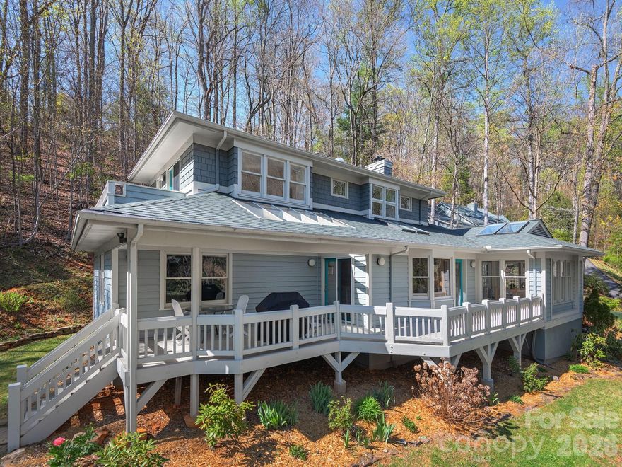 A rare find for the discerning architecture enthusiast! Featured in Southern Living Magazine in 1989, this contemporary custom-designed home offers timeless architectural character rarely found in today's market. Curved walls, box bay windows, soaring beamed and vaulted ceilings, and skylights bathe the main level in natural light, while hardwood floors, solid wood trim, and custom oak cabinetry with hand-crafted pulls speak to exceptional craftsmanship throughout. The garage and main entry are conveniently located on the lower level, along with over 1,300 sqft of unheated bonus space: currently set up as a home gym and studio. The sun-drenched all-seasons room welcomes you to the main level, flowing seamlessly through French doors into the stunning living room, where a gas log fireplace is beautifully flanked by custom built-in shelving. The kitchen and dining area shine with granite countertops, stainless steel appliances, a large single-basin sink, skylights, and a spacious pantry, with direct access to the front porch stretching the full width of the home. A spacious main-level bedroom, full bathroom, and dedicated laundry room round out this thoughtfully designed floor. Upstairs, the private primary suite is a true retreat: walk-in closet, a soaking tub overlooking lush nature views, double vanity, and a private balcony to breathe it all in. Designed by architect Jim Samsel, every detail of this home works in harmony with its beautifully situated lot. A private mountain escape, just 10 minutes from the vibrant dining, arts, and culture of Downtown Asheville. The garage was built as a two-car garage: current owners installed non-load-bearing interior wall that can easily be removed to revert back to two car-garage.
