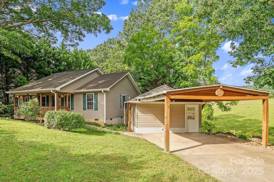 Beautifully maintained and full of charm, this 3-bedroom, 2-bath home offers easy one-level living in a peaceful East Asheville setting. A covered rocking-chair front porch sets a welcoming first impression, while pastoral and mountain views enhance the sense of place. Inside, vaulted ceilings and abundant natural light highlight the open living area, where a cozy fireplace adds warmth and character. The skylit eat-in kitchen provides both style and function, perfect for everyday living or hosting friends. A spacious primary suite features a walk-in closet and dual vanities, offering comfort and convenience. Outdoor living is just as inviting, with a back deck and generous yard ready for relaxation or entertaining. Adding to the appeal is a large detached finished building with its own half bath—ideal for a studio, workshop, or creative space. Tucked away yet minutes to downtown Asheville and the Blue Ridge Parkway, this home is the perfect balance of comfort, charm, and location.