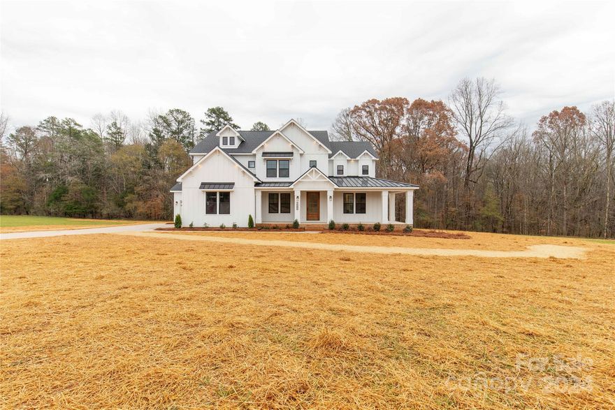This stunning modern farmhouse is nestled on a gorgeous 5+ acre tract in Clover, SC, and is just waiting to welcome you HOME. As you pull up into the driveway you'll be in awe by the curb appeal of the white exterior, black accents, and wrap-around front porch. The home offers a 2 car garage and an additional single-car carriage garage for that extra storage. Inside you will find carefully curated selections from top-of-the-line Z-line gas range,  Moen plumbing fixtures, & matching hardware throughout. The great room will feature a coffered ceiling and a custom focal point fireplace. Boasting a primary suite on the main level, and a second primary suite on the 2nd floor, both with luxury en-suite baths. There are also 3 additional bedrooms, 2 additional full baths, and a bonus room upstairs. For a touch of extra convenience, there are 2 laundry rooms, one on the main level & 2nd floor. Up to 2 Horses and/or cows are allowed.