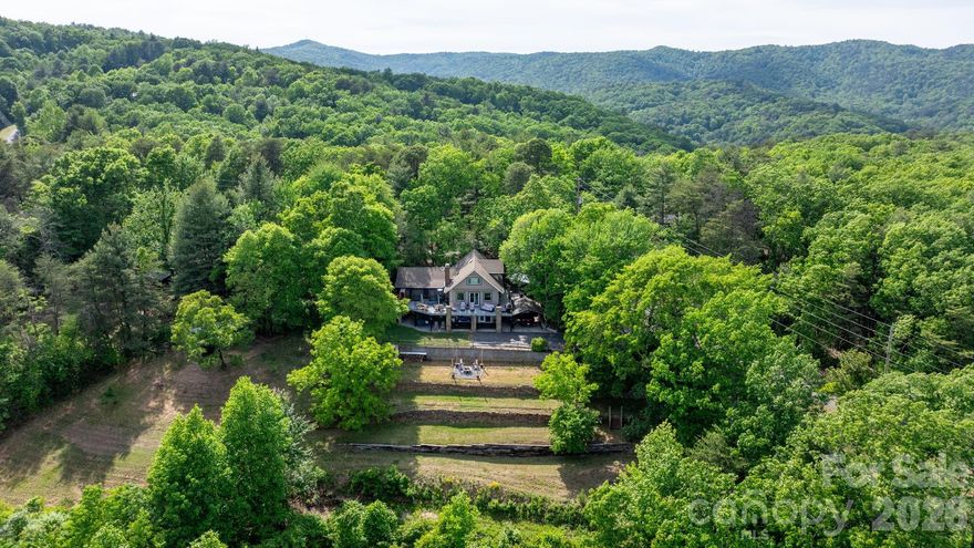 Stunning mountain cottage w/breathtaking eastern sky views! Perfect for unforgettable sunrises & moonrises over the mountains. Located near the entrance to South Mountain State Park in the gated community of Pine Mountain Lakes, this beautifully maintained home offers the perfect blend of comfort, craftsmanship, & natural beauty. With natural rock walls, a freestanding swing, lavish fire pit area, & peaceful surroundings that frequently attract deer, the exterior simply welcomes you home. The property features a variety of fruit-bearing plants & vines including fig, apple, pear, pecan, muscadine, blackberry & roses. Additional outdoor features include upper & lower driveways, covered parking, a 3-bay tractor shed, storage shed, garage workshop (392 ft², exterior access only) & a lower-level covered patio. A remote-controlled retractable awning provides shade over the composite wraparound deck w/ramp access, creating the perfect space to relax & take in the incredible mountain views. Inside, the main level offers an open layout w/parquet wood flooring & expansive windows that capture the spectacular scenery. The well-appointed kitchen features granite counters, corner pantry, instant hot water at the sink & a dine-in island w/additional bar seating. The living room is filled w/natural light & showcases a beautiful stone fireplace w/gas logs crafted from stones sourced from Fontana Dam. The open dining area offers the same stunning views & direct access to the wraparound deck. A convenient half bath is located just off the kitchen. The spacious main-level primary suite provides a private retreat w/sitting area, double closets & private access to a screened porch overlooking the mountains. The ensuite bath includes a walk-in shower, jetted tub, bidet, dual sinks, large linen closet & timed heat lamp. Throughout the home you’ll find solid wood doors & the stairway was crafted from 100+ year-old barn wood while the beams and the parquet flooring was milled directly from this land, adding unique character & history. Upstairs are two additional bedrooms, each w/wood floors, ceiling fans & mini-split systems. One bedroom includes two attic access doors, while the other offers built-in shelving & cubbies. A shared bath w/Corian countertops, tub/shower combo & large linen closet serves the upper level. The lower level provides additional living space w/marble flooring, a second gas log fireplace crafted from Fontana Dam stone, built-in credenza & a full bath w/walk-in shower. Behind the wine cellar door is the laundry & utility area featuring a commercial-grade sink, non-slip tile flooring, storage shelving & a propane tankless water heater. The home also includes a Carrier propane furnace (2013) w/dehumidifier & central air conditioning. With newer Champion windows & select doors, exceptional craftsmanship & panoramic eastern-facing mountain views, this special property is perfectly suited as either a full-time residence or a relaxing mountain getaway, offering a rare combination of privacy, comfort & unforgettable scenery.