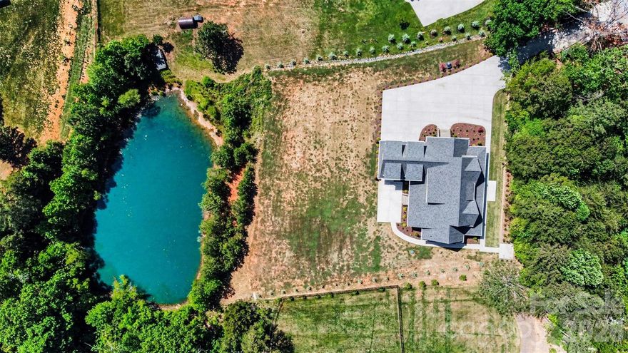 Set behind gated entry on a private two-acre parcel inside the I-485 loop, this custom farmhouse delivers rare privacy without sacrificing proximity. The setting is framed by mature trees and tranquil pond views, creating a peaceful backdrop for everyday living and entertaining. A striking modern exterior is accented by imported European windows and doors, showcasing refined architectural craftsmanship throughout.

Inside, wide-plank white oak floors and designer-selected lighting establish a clean, elevated aesthetic. The main level is anchored by a spacious primary retreat with direct patio access, a customizable walk-in closet, and a spa-inspired bath featuring a seamless zero-entry shower and deep soaking tub. The kitchen commands attention with quartz surfaces, Z-Line appliances, an expansive pantry, and a walk-through scullery equipped for serious hosting, including an additional oven, dishwasher, and prep sink.

Purpose-built spaces enhance daily function, including a dedicated workstation, an oversized laundry and drop zone with convenient driveway access, and a secondary full bath on the main floor. The three-car garage includes a drive-through third bay and is complemented by an additional drop zone off the interior entry. Outdoor living continues on the covered rear patio with fireplace, overlooking a level backyard ideal for gatherings or future enhancements.

The upper level offers three generously sized bedrooms—one with a private bath—along with multiple flex and entertainment areas complete with a kitchenette, providing space to unwind, host, or adapt to changing needs with ease.
