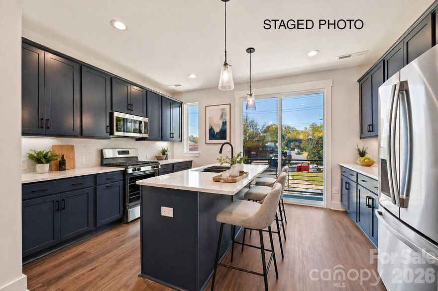 NoDa townhome offers 4-story living with 2 outdoor spaces. Make a statement in this bold kitchen, with 42" nautical blue cabinets & matte black hardware, quartz counters, LED under-cabinet lights, pantry, trash pullout, large undermount sink, & GE stainless steel appliances w/ gas range & fridge included. Off the kitchen is a small balcony with TREX decking. Nook by stairs/dining has space for a desk. 3rd floor has laundry w/ GE stacked washer/dryer included. Premier Suite has plenty of space for a king-sized bed; private bath features nautical blue cabinets, quartz counter, tiled floor & tiled shower. Guest bath is located next to the guest bedroom, w/ tiled floor & quartz counter. Great 4th floor w/ Rec room & Powder plus Rooftop Terrace w/ TREX; can double as a guest bedroom or home office. Walking distance to restaurants, with easy access to Uptown Charlotte and N. Davidson St.  and Plaza Midwood. 2-car tandem garage PLUS private driveway is included! 9' ceilings throughout. LVP floors the 1st & 2nd floors & 3rd floor hall with oak treads on stairs.