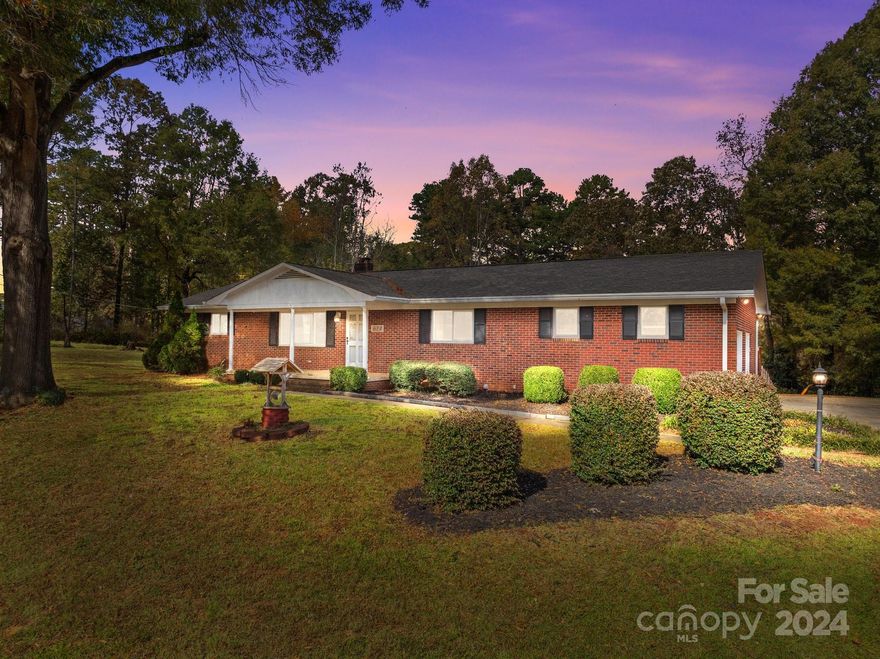 Welcome to this charming, fully-brick home nestled on nearly an acre of land, offering privacy and a lovely view of the woods from your back yard. Enjoy your mornings and evenings on the rocking chair front porch, then step inside to find spacious living areas and plenty of natural light due to new windows throughout the house. The main level boasts an oversized 2-car garage for easy access, while a basement garage provides additional storage or workshop potential. The fenced-in backyard is perfect for gatherings or simply soaking in the tranquil scenery. This home’s blend of style, space, and outdoor beauty is ideal for those seeking comfort and a touch of country charm, all within easy reach Downtown Kannapolis.