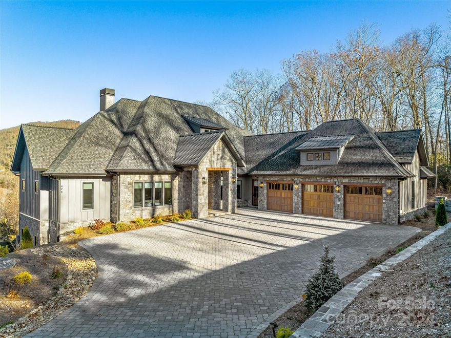 Discover this exquisite home in The Cliffs at Walnut Cove featuring year-round mountain views. Completed in 2023, this home offers a sprawling open floor plan, volume ceilings, chef's kitchen with waterfall quartzite countertops, designer lighting, spa like primary suite and 4 decks of outdoor living that include firepits, grill kitchen and hot tub. An ideal setting for generations to unite in unparalleled high-end style, including elevator.  The main level offers a luxurious living experience, while the lower level extends the allure with an additional family room and 2nd full primary suites, catering to multi-generational living. The lower level also offers a spacious room for exercise, home theater or golf simulator.  Whether hosting guests or enjoying quiet family moments, this home provides all the essentials for a harmonious lifestyle. Welcome to Walnut Cove, where a single membership opens doors to a world of activities and friendships across seven communities in NC and SC.