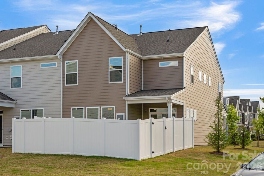 There's a version of home ownership where everything is already handled.
The fence is in. The blinds are hung. The garage is finished. You open the door and the space receives you.
6211 Nandina Drive is that home. Ready for you to make it yours from day one. No wait. No add-ons. No upgrade costs. Just the foundation of a settled life, already laid out and waiting for you.
The kitchen is where this home earns its reputation. Gas range, quartz countertops, marble subway tile backsplash, and an island with undermount sink and pendant lighting above.
 The family room opens directly to it so whoever's at the barstools stays in the conversation, whoever's cooking never misses a moment. 
The dining room carries its own personality, anchored by a chandelier and sliding glass doors that open to the covered patio and private fenced yard beyond. 
Inside and outside, the flow between them is seamless.
Upstairs, the open loft creates breathing room. A second living area, a home office, a place for the household to spread out without losing each other. The primary suite is quiet and considered — frameless glass walk-in shower with built-in bench and mosaic accent tile, double vanity with quartz counters, natural light from a well-placed window. The secondary bath offers a full tub-shower combo with large-format tiled surround and niche shelving. Every finish chosen with intention.
Off the garage entry sits a built-in mudroom that quietly holds the household together. Beadboard paneling, a bench, two cubbies beneath. The detail you don't know you need until you have it every single day.
As an end unit, this home lives larger than its footprint. More windows. More light. More separation. And the location within the community is its own reward located directly across from the walking trail, pool, dog park, and green space. Not a drive. Not even much of a walk. Just across the street.
Harrisburg schools. Minutes from shopping, dining, and UNC Charlotte. A neighborhood with a genuine sense of community and the quiet to match. 6211 Nandina Drive isn't waiting to become something. It already is.