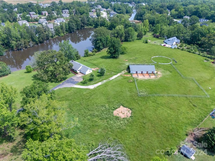 Welcome to this very special property with over 10 acres of land overlooking two ponds with stables and cottage. Enter into a light filled, open-concept floorplan with vaulted ceilings. Large picture windows throughout the main level of this home bring the outdoors in with expansive views of the property. Living room with stacked stone fireplace opens to dining area and kitchen.  Primary bedroom located on the main level with walk-in closet and en suite bath.  Secondary bedroom/office also on main level with an additional full bath. Lower level w/ 2 bedrooms/bathrooms, office and flex room. 2 stall garage with walk-up storage w/ detached one car garage on property. A horse lovers dream with hay loft and stable including several stalls open to riding pen and pasture. Small one-room cottage with full bath overlooking the smaller pond. Enjoy the privacy of country living yet close to everything Rock Hill has to offer. Property sold as is. Back on market no fault of the sellers.