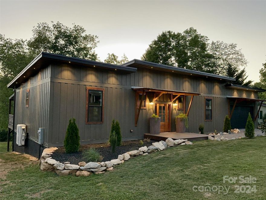Striking, newly constructed, ONE-LEVEL home in highly desirable Lake Junaluska(and very close to the lake). 3bed, 2 bath, 1848 sq ft(excluding the attached and insulated 2 car garage), the architecturally modern home has a great deal of custom features, including: large composite back covered deck that looks out toward lake and mountains, custom-quality interior finishes(quartz counters, live edge kitchen island, tiled bathrooms, etc), high ceilings, primary bedroom, pantry/laundry room, office, etc. Other features and upgrades include: soundproofing insulation throughout home, high speed internet access point, metal roof(and leaf guards), electric car charger and hot tub-ready electric. The nearly level lawn is highly usable, and the property is conveniently located to downtown Waynesville(8 min) and Asheville(31 min). Check out the Matterport virtual tour at https://bit.ly/3WJU0PS