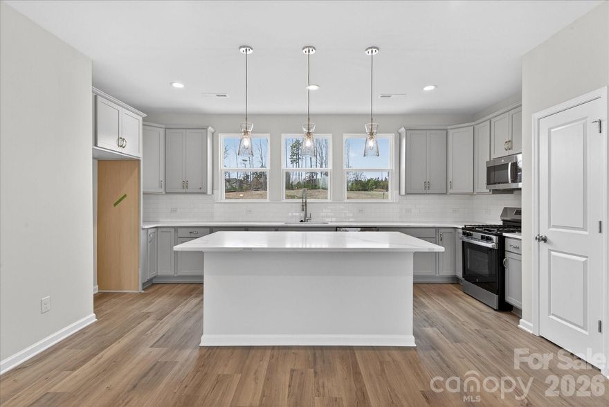 New 3-story townhome in Charlotte's University area, with a private bath in every bedroom. Walk to Toby Creek Greenway, with easy access to the light rail for heading to Uptown Charlotte, South End, and beyond. The first floor has a 2-car garage plus guest bedroom with private bath. Open-concept living on the second floor, with 9' ceilings and a private terrace with green space views and Trex decking. Layout the space with a separate living room and dining area, or you can use the large kitchen island as a dining table, with barstools on both sides. The spacious kitchen boasts 42" grey cabinets, quartz counters, tile backsplash, double pullout trash cabinet, sleek stainless steel Moen faucet, and GE stainless steel appliances with a gas range, plus a pantry closet. The third floor has a laundry closet large enough for a full-sized stacked washer/dryer. Nice sized Primary suite has a walk-in closet and bathroom with large tiled shower.  All bathrooms feature quartz counters, grey cabinets, and tiled floors. LVP flooring is at the entry and throughout the second floor, with oak treads on the first set of stairs. Located about 2 miles from UNC Charlotte, Brixton is set back in a quiet location, yet close to everything. Driveway plus on-street parking is included.