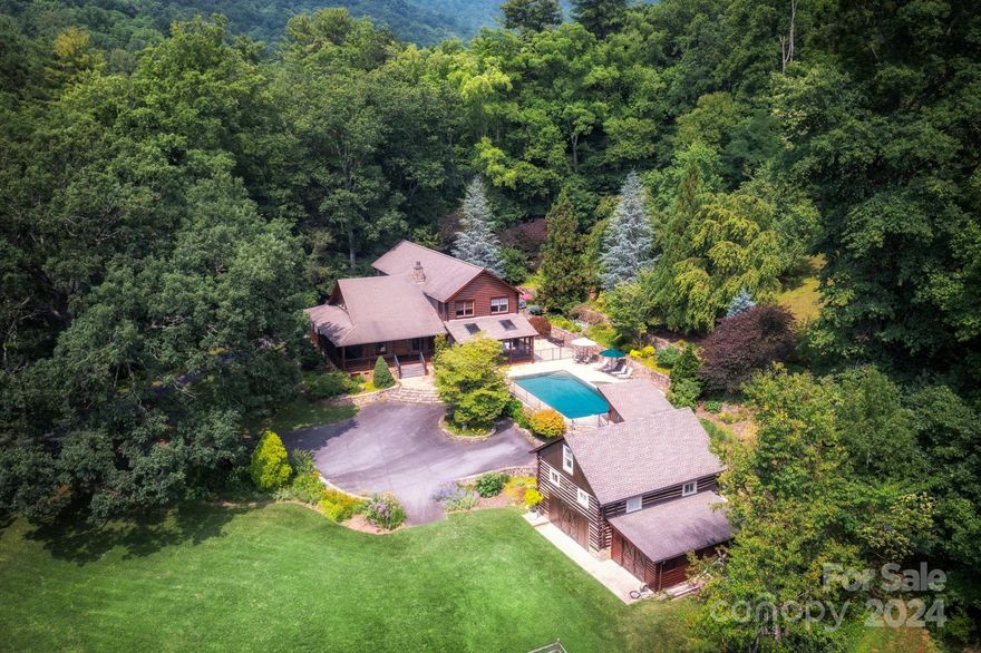 Stunning property in North Asheville’s Beaverdam Valley — a hidden gem about three miles from Blue Ridge Parkway trails and approx 10 mins. from downtown. This unique property on 14 acres includes a beautiful, modern log home; charming, historic barn; exquisite stonework; swimming pool and hot tub, plus meticulously maintained grounds. Home features a wraparound covered porch, great room with a vaulted pine ceiling and wood-burning stone fireplace, and a private primary suite wing. Open and bright, with many windows and a freshly painted interior. Come home to a peaceful setting — stunning trees, a creek running along the road, and a wide-open, level field for gardening/play. No shortage of storage: two-car garage, many closets within home, and more space under the barn. This is a rare find so close to town; outside city limits (county taxes only), yet within Asheville City Schools district. See brochure, video, plan, and virtual tour. Water and power are on - no known storm damage.