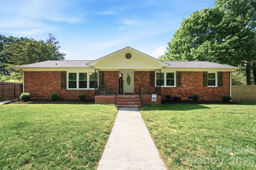Welcome home to this charming, move-in ready brick ranch nestled in a quiet, established neighborhood in Monroe.
From the moment you arrive, you’ll appreciate the timeless curb appeal and peaceful setting, highlighted by a spacious circular driveway that provides additional parking.  You step inside to a warm and inviting living space filled with natural light, highlighted by beautiful hardwood floors and a classic brick fireplace—perfect for cozy evenings or gathering with family and friends.
The layout is both functional and flexible, offering multiple living areas and a dedicated dining space that can easily adapt to your needs.
The updated primary suite provides a comfortable retreat, featuring a renovated bathroom with a dual vanity and a spacious tiled shower designed with both style and convenience in mind.
Out back, you’ll find a covered porch ideal for relaxing or entertaining, overlooking a large, private yard with plenty of room for outdoor activities, gardening, or simply enjoying the space. A detached workshop/shed adds extra storage and versatility.

Conveniently located just minutes from downtown Monroe and an easy drive to Charlotte, this home offers the perfect balance of comfort, convenience, and community.