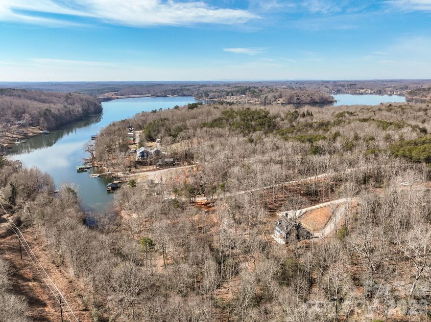 This one-of-a-kind, private, lakefront home situated on a stunning 4.66-acre lot offers the perfect blend of seclusion and natural beauty. Soaring cathedral ceilings flood the home with light and create an inviting atmosphere. The cozy living room features a wood-burning fireplace ideal for gatherings, while the primary bedroom offers its own charming wood-burning fireplace for ultimate relaxation. Upstairs, find two additional spacious bedrooms, a large full bathroom, and a flexible bonus/office room. Key highlights include two wood-burning fireplaces total, a walk-in pantry, and a partially finished walk-out basement with double French doors opening to a serene patio in the fenced backyard — perfect for outdoor entertaining, morning coffee, or simply enjoying the tranquil surroundings. Step outside to breathtaking natural surroundings: a picturesque gravel driveway lined with flourishing fruit trees (peach, pear, plum, and apple), a meandering natural spring, and direct lake frontage with a dockable shoreline on Lake Lookout. Water enthusiasts will love the easy access to a nearby public boat launch for fishing, kayaking, boating, and more. Additional practical features: a computerized well with filtration system, outdoor gas hot water heater with circulation for instant hot water, and a detached heated/cooled two-car garage PLUS an ON-GRID 61" x 91" 800 WATT SOLAR PANEL. The property is accessed via two driveways (one concrete, one gravel) for added convenience and privacy. As a unique bonus, it includes a custom-built, whimsically decorated Gypsy Cart for your own special escape! This exceptional home is more than just a residence — it's a peaceful lifestyle retreat where every day feels like a vacation. Close to parks, shopping, and outdoor recreation in the desirable Statesville area. An exceptional opportunity to own water lake property for under $1,000,000! Transferable home warranty! The wood Planer, Table Saw, Generator, Air Compressor, 3D printer, window AC units are not for sale and do not convey.