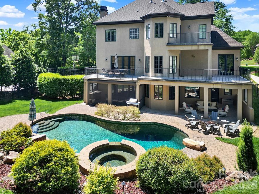 You've arrived...Beyond the gates of this premier luxury enclave, during the drive home you begin to relax, shoulders lower, breath deepens, the day loosens its grip. Pull into the garage, where an electric charger quietly restores your car while you do the same. The stone and stucco façade stands in timeless confidence, neither trendy nor trying, simply correct. Inside, solid hardwood floors stretch across the main level, grounding the home in craftsmanship and intention. A first-floor office awaits those work-from-home days… or the convincing appearance of them. The formal sitting room and dining room are made for the kind of evenings that begin with, “It’s been far too long—I’m so glad we finally did this.” Conversations warm, laughter settles in. From there, the home flows effortlessly into the chef’s kitchen, where serious sauce reductions happen alongside stories that linger well past their planned ending. Down a step, the sunken den invites shoes off, defenses down. Here, discussions of art, politics, and the day’s events unfold with equal parts passion and validation, occasionally spilling out onto the terrace when fresh air feels necessary. Upstairs, the owner’s retreat waits patiently. Vaulted ceilings, abundant natural light, and a private balcony create a space that quite literally opens its arms at the end of the day. Two closets—because one simply wouldn’t do. Four additional bedrooms complete the level, ready for family, guests, or futures yet imagined. When it’s time to gather for New Year’s Eve, summer soirées, or celebrations that require no reason at all—the lower level comes alive. A dedicated cocktail bar sets the stage for flights of fancy while a charcuterie board takes shape in the full kitchen. Guests settle into the family room, drift to the screened porch, or make their way outdoors where the pool and hot tub await the right crowd at the right hour. A covered patio offers welcome shade on warm summer days, extending the living space into the outdoors with ease and elegance. Last but not least is the 6th bedroom on this level with its own entrance for guests to come and go quietly or for that family member that needs to stay longer. High School students in the house can get their steps in by walking to school, quicker for that late riser. If the furniture in the home is your style, the owner is willing to negotiate. This is the house you’ve imagined, you've played out in quiet moments and grand gatherings alike. And now, it’s no longer a dream.
