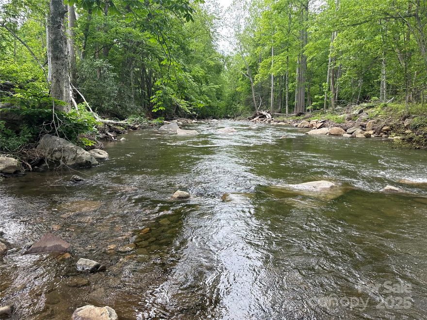 Fisherman’s Paradise – Rare Trout Stream Retreat; This is more than a piece of property—it’s a place where pride, purpose and connection naturally take root. With 314 feet of pristine, easily accessible frontage on Little Rock Creek, a designated Class A trout stream renowned for the Casting For Hope Fly Fishing Competition, this land becomes part of your story. Walk the entire riverbank, step straight into the shoals, deep pools and cascading rapids (30–40 feet wide), and experience a setting that invites care, commitment, and long-term thinking. Stocked by NC Wildlife, it’s a true angler’s dream and a retreat that offers meaning well beyond closing day.
Located on a paved, state-maintained dead-end road, just 4 miles to Bakersville and 25 minutes to Burnsville, the property strikes that rare balance of convenience and seclusion. The gentle topography includes a cleared, graded lot with gravel driveway and building pad—ideal for a mountain cabin, private vacation retreat, glamping setup or RV pads. A 3-bedroom septic system installed in 2022 and a strong onsite spring (awaiting connection) further enhance its value and usability. No Restrictions, No Zoning.  
Land like this offers something few other investments can: freedom, privacy, lifestyle flexibility and the opportunity to build something lasting. Over time, it becomes a place with history, memories and meaning. In a world where so much feels temporary, this creek front retreat stands apart. Once people fall in love with land like this, they rarely look back—not because they can’t sell but because they don’t want to. In a world that moves fast and feels temporary, this is where you can put down roots—without giving up convenience. A truly rare creek front gem—call today for a private tour.