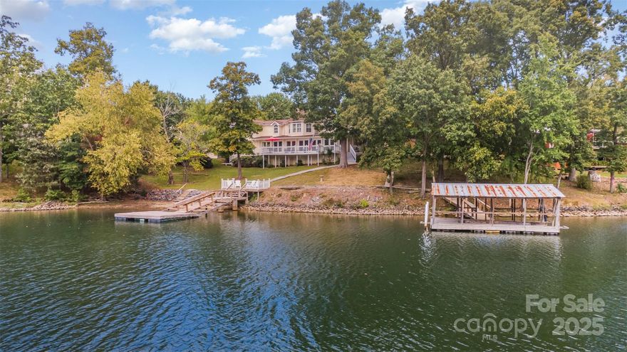 Located within an exclusive gated neighborhood inside The Palisades, this rare .73-acre waterfront property offers a lifestyle defined by tranquility and breathtaking natural beauty with NO HOA fee. Set along 185 feet of shoreline, this home delivers year-round panoramic views of Lake Wylie paired with 2 docks. Inside you’re greeted by open-concept living that opens directly onto a wraparound deck, offering seamless indoor-outdoor living where entertaining, dining, and relaxation all come with an incredible view. The primary suite is conveniently located on the main floor, while 4 additional bedrooms are on the upper level, most of which can be enjoyed by a lake view. This property is one of the very few with two deeded docks, giving you the flexibility to host multiple boats and watercraft- an extraordinary feature that sets it apart on Lake Wylie. Outside, the property includes a detached garage, a storage shed, and an additional utility space—perfect for keeping recreational gear, tools, and lake essentials organized and ready for use. This generous .73-acre lakefront property provides a special opportunity with a ton of potential.
