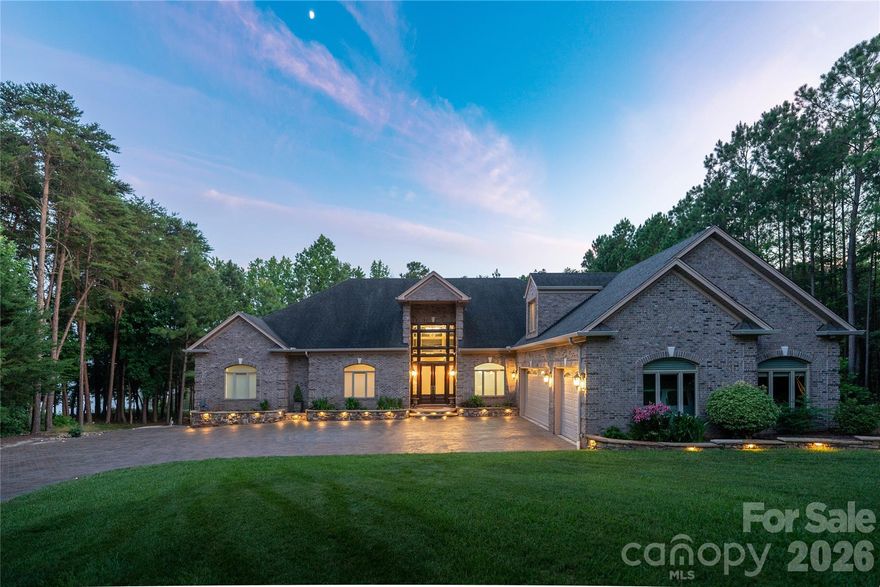 This spectacular 10,144 square foot waterfront home has a private boat dock and indoor pool/spa. If you're looking for a private retreat in an exclusive community, this is the home for you.
Nestled on the shores of Badin Lake with over 200 feet of private shoreline, this premier waterfront retreat offers captivating lake views and effortless lake living. Just steps from the renowned Old North State Club, ranked among Golf Digest’s top courses, the property features a lighted dock with a boat lift and three Jet Ski lifts. An exceptional indoor pool retreat awaits with travertine floors, cedar storage, dry sauna, stone fireplace, and hot tub, designed for year-round enjoyment in a peaceful setting. Four on-suite bedrooms, with a huge primary suite. Two full kitchens(main level and basement) with a dumbwaiter for effortless connection. Updated appliances. New dehumidifer in the pool/spa. Four A/C units were replaced in 2020. Other standout features include, Sonos Sound System and HikVision security system to name a few. Please see the attached features list for more details. The home is located in the gated community of Heron Bay.