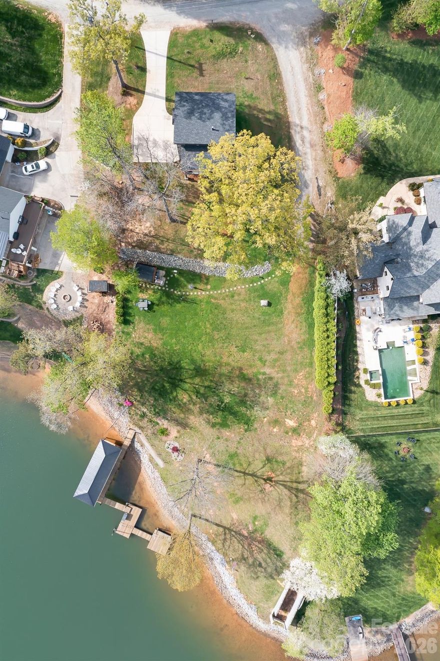 Price Improvement and ALL furnishings included for a turn key move in ready before the Memorial Holiday weekend and start living the Lake Norman life!  Over 1 acre of Magnificent waterfront unrestricted land (NO HOA) with approx 217' of stabalized shoreline, a 40' covered fixed boatslip and additional floating dock.  Build your future home while you live in the 2024 build secondary home with 2 bedrooms a dedicated office or you could use this as a 3rd bedroom and 2 car garage.  No expense was spared during the construction.  The complete Kitchen Aid appliance package, Additional holiday dishes can be stored in the hidden cabinets in front of the bar stools, Tankless propane water heater, Sono's sound system indoor and out, complete wifi home and wifi at the dock, Lake fed irrigation pump installed, Power at the dock for a future lift, Smart home wiring, Generator transfer switch installed, 30amp Electric car charger in the garage and so much more.  You never have to worry if you have enough dock space for your friends and family.  Enjoy every night sitting on your covered porch or on the covered dock with a seating area.  Fall firepit nights with the peace and tranquility you have been searching for.  Bring your own builder or have a chat with the builder that constructed this wonderful open floor plan contemporary home.  Did we mention there is a former block boathouse that could be converted into a Jimmy Buffet style waterfront retreat.  Long range waterfront views from the primary bedroom, great room, kitchen and home office.  You can enjoy Lake Norman year round with deep water even when Duke energy brings the lake down during the winter months.  You can realize what you have vizualized in your new construction home or just enjoy the current home and the lay of the level land.  We've included a sample rendering of the primary home which was going to be constructed with the garage and front door on the street side with a wall of sliding glass doors for the bunk room, bathroom and hall. Basically flipping the garage level from back to front.  To access the home office or could be used as a 3rd bedroom, enter throught the garage.  Magnificent Waterfront views from the sliding glass door. Maximum building footprint is 50 x 60