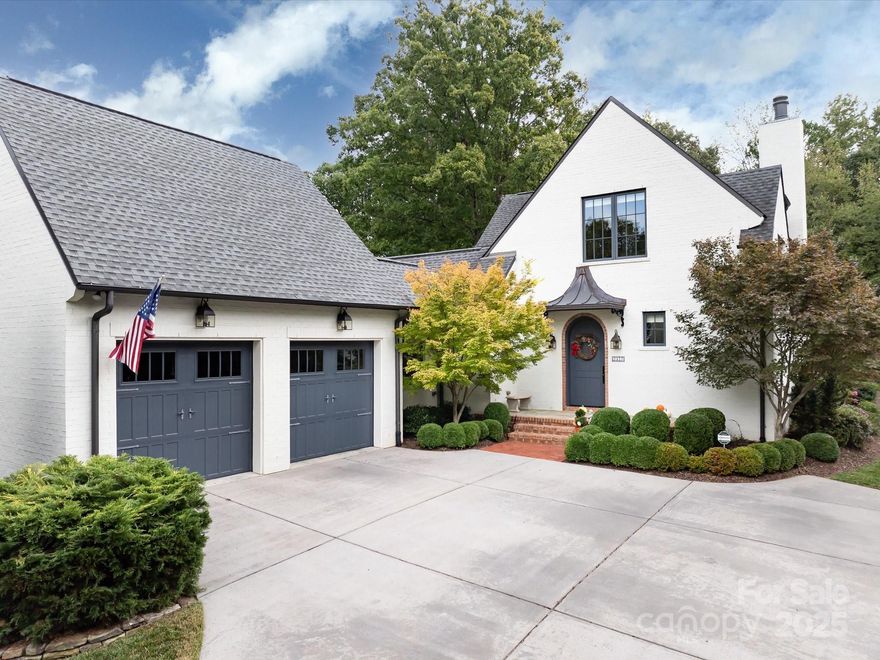 Nestled on a corner lot in Giverny, this custom English cottage exudes charm & the finest finishes. Designed by architect Brad Wright & built by Everett Custom Builders in 2016, the exterior features painted white brick, a copper portico over the front porch, Kolbe casement windows & a prominent chimney.  A two-story foyer welcomes you inside & details of custom craftsmanship such as 5-inch wide-plank oak wood floors & extensive trimwork appear.  A generously-sized living room with gas fireplace & built-in bookcases invites you in. The kitchen is equipped with high-performance Thermador & Samsung appliances. Quartz counters, marble subway backsplash & a Shaws fireclay sink add to the cottage charm.  Gather around the large island or in the sunroom to enjoy walls of windows that flood the home with natural light.  Built-in storage options abound in the extended mudroom & into the laundry room. Designed for convenience & privacy, the main-level primary suite offers a quiet retreat.  The en-suite primary bath is a luxurious space with dual vanities, large walk-in shower & a wall of built-in cabinets & drawers. Upstairs, the hallway features built-in bookcases leading to two additional bedrooms. A shared bathroom features tasteful tile-work & dual sinks. Notice the walk-in attic space off the far bedroom with potential to expand above primary suite. Outside, enjoy the patio with permanent awning, expansive lawn & mature landscaping with stacked stone planting beds.  Attached two car garage with extended space for additional storage.  Located in the heart of SouthPark, this home offers a walkable neighborhood & close proximity to restaurants, shopping & the airport.