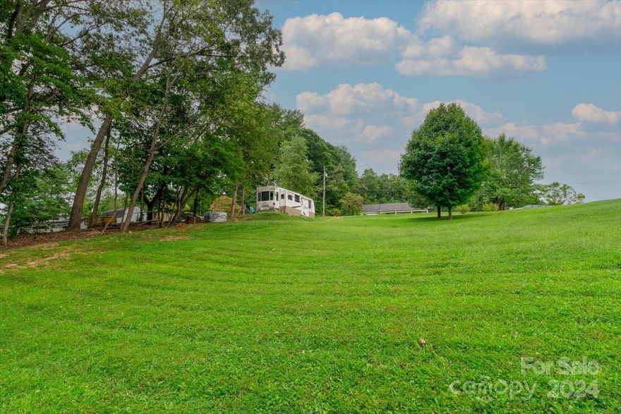 Build your dream home or investment property on this gently-sloping, clear lot with mountain views. Located less than 15 minutes from downtown, yet outside city limits, this lot conveys with a Woodfin short-term rental permit. This lot is 1 mile away from the world-class river wave being constructed on the French Broad River! See aerials in the video. There is a Woodfin water meter installed and 4-bedroom septic system already in place. Electricity is already run to the site as well. What could be easier?! This lot is ready for development! While you build, you can live in the on-site camper, which is negotiable.