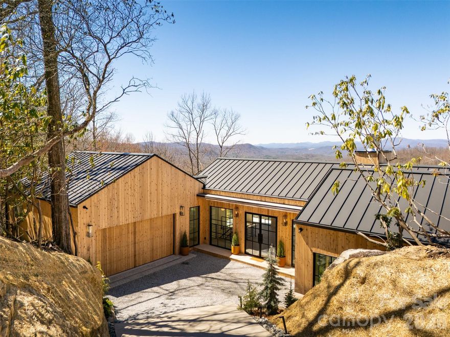 Welcome to 1882 Connestee Trail, the pinnacle of Mountain-Modern luxury in the sought-after gated community of Connestee Falls.

This exceptional high-end, new construction home blends natural materials with refined design, offering breathtaking long-range mountain views from nearly every room. Wrapped in rich cedar wood siding, the exterior harmonizes beautifully with its wooded surroundings, creating a striking architectural presence. Carefully tucked into the surrounding landscape, the home offers just under 3,200sf of living space with 4 bedrooms and 4.5 baths on a large double lot totaling 1.3 acres, ensuring ultimate privacy and serenity.

Inside, clean lines and high ceilings frame walls of glass that flood the home with natural light and showcase the incredible Blue Ridge Mountain vistas.  A carefully curated design palette results in a stunning blend of sleek modernity, and timeless traditionalism. Warm, white-oak flooring & dark charcoal mill-work finishes add depth and texture throughout. The chef’s kitchen features honed marble countertops, custom cabinetry, and top-tier appliances.

The open-concept living and dining spaces flow seamlessly to expansive outdoor decks, inviting you to enjoy cool mountain breezes and unforgettable sunsets. Wood Burning Fireplaces adorn both the inside and outside living areas for year round ambience and comfort. Modern amenities include a full Butler's Pantry, a 2 Car Garage, and a luxurious dry Sauna. Ample bedroom suites provide spa-inspired retreats, while thoughtfully designed living areas offer both comfort and sophistication. This is elevated mountain-living at its finest.  

The main floor features a generous Primary Suite complete with his & hers walk-in closet, dual shower heads, and a soaking tub. On the lower level, guests will find 3 additional bedrooms all with en-suite baths, mountain views and private deck space.

Located within Connestee Falls, residents can enjoy access to miles of hiking trails, pristine lakes, golf, tennis, pickleball, and clubhouse amenities, including an all new wellness center—all just minutes from the charm of downtown Brevard’s shopping & dining.

A rare opportunity to own a completely turn-key, refined Mountain-Modern sanctuary, where architecture and nature exist in perfect balance.