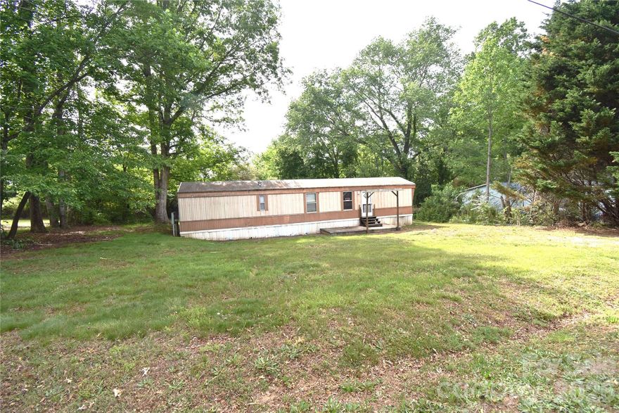 2 bedroom, 1 bath singlewide home situated on a nice level lot with plenty of potential. The open living room and kitchen area create a comfortable layout with great possibilities for updates and personal touches. A deck just off the living room overlooks the backyard, offering a relaxing outdoor space to enjoy. The level yard provides room for gardening, recreation, or additional outdoor features. Conveniently located near downtown Hudson and the Cajah Mountain area, this property offers easy access to shopping, dining, and local amenities. Property is served by a septic system and well, with a City of Lenoir water tap available at the street. Sellers currently researching the age of the singlewide home. Home is being sold as-is and is cash only. Great investment opportunity or project property with lots of potential!