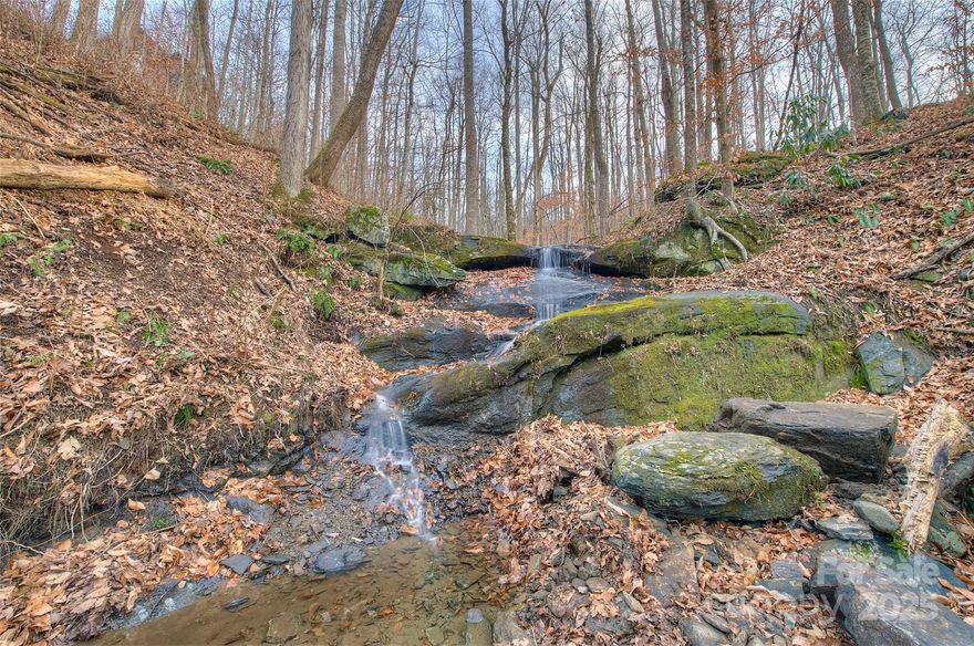 Located directly between Spruce Pine and Burnsville, just off US Hwy. 19-E in the Shadowood Community is a very special and unique acreage, carved out of a mixed hardwood forest in these magnificent mountains, is 4.9 incredible acres featuring and a brand new three-bedroom septic already installed.  You only need to decide where to place your home and well. 
But WAIT… There’s More!  A rushing spring fed live water creek runs 400 +/- feet of the property with a good water falls of 10-12 feet, and multiple smaller falls ranging between 3-6 feet affording many cascades and wading pools for pets and children from ages 2 to 92! 
Live water so pristine that you could drink from it!  Imagine that first summer night with the open bedroom windows in your new home… listening to your very own private natural bold creek singing Appalachia’s lullaby as you nod on off to the best sleep you will ever experience on earth.  There is a nice path carved out to walk and see the falls. 
The covenants are light, even affording you the opportunity to stay in a camper as your home breaks ground and continues through completion.  On the same note, your investment is protected with appropriate and reasonable deed value protecting covenants. 
  The property holds value that ever increases as fewer and fewer prime tracts like this are available in such a coveted area.  So go ahead, and build your home, and if you decide to sell in a year or two, you will understand what a sound investment you have made.  
The property is perfect for building your beautiful year-round residence, or a vacation retreat at less cost per square foot than in most other sections of the country.  Also, its important to acknowledge: THE DEGREE OF FREEDOM IS HIGH, & PROPERTY TAXES ARE LOW! 
?The combination of elevation, timber, and topography create a wildlife-rich environment.  From the native whitetail population turkey, quail and abundant songbirds, butterflies, fox, rabbits, American bobcats, and black bear. 
The entire region is known for its national forest and wilderness areas, and you are just a couple miles from the famous Toe River where there is world-class canoe and kayaking, along with a high concentration of the largest specimens of our native brook/speckled trout attracting fly-fishermen from all over the US.  In addition to this world-class, clear-water angler’s dream, one can enjoy this backwater all the way from Spruce Pine,  to the Mississippi on into the Gulf of America.  
This beautiful homesite is approximately mid-way between New York and Florida, and is easily one days drive from 60% of the entire US population— New York, Philadelphia, Washington D.C., New England, Florida and the Mid-west. 
No matter the road you take, to or from here, it’s always the “scenic route!”  Your legacy awaits— 
You are just 5 minutes away from downtown Spruce Pine, The Grassy Creek Golf and Country Club, and the Blue Ridge Regional Hospital; 10 minutes to the Blue Ridge Parkway and 20 minutes to the Linville Falls Winery— perfect for wine, music and weekend relaxation; 5 minutes aways from the famous Penland School of Crafts;  You will be 10 minutes to downtown Burnsville, or 30 minutes to Lake James, Marion, and I-40; 50 minutes to Asheville, NC; 60 minutes to Johnson City, TN, and the Tri-Cities Airport.  This community is two hours from Charlotte, NC.