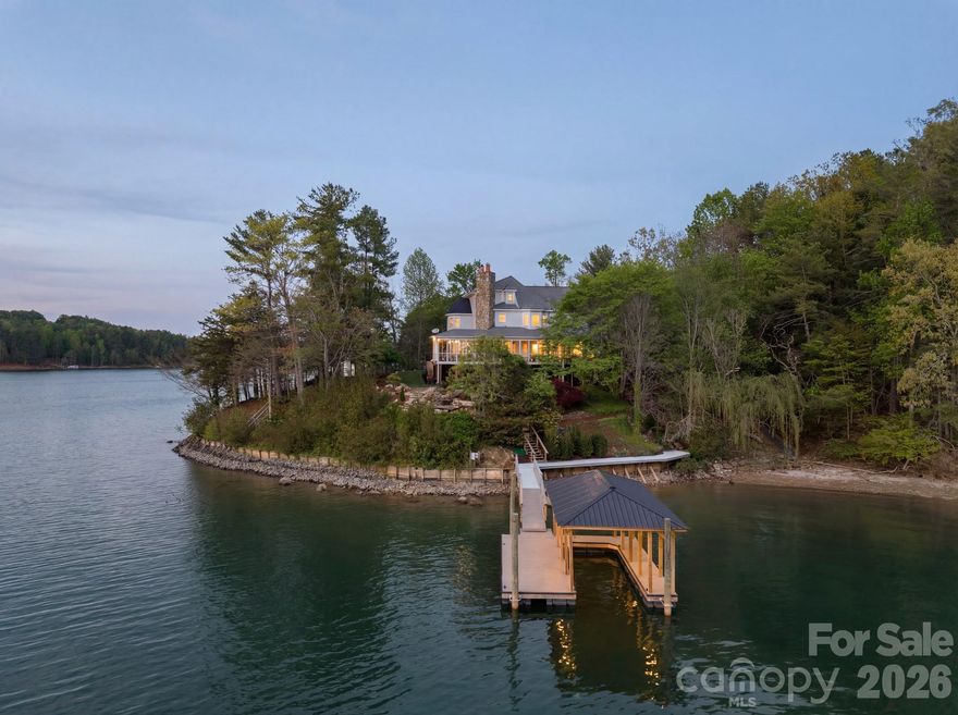 Waterfront estate situated on its own private peninsula along the pristine shores of Lake James. Sweeping, unobstructed views of the lake and surrounding mountains greet you from the wrap-around porch where Golden Hour sunsets are nothing short of extraordinary. The property is designed for easy indoor-outdoor living and entertaining with thoughtfully designed water features, a large green space (did someone say badminton?), a brand-new dock, a fire-pit set on the point, and 450 feet of private shoreline.

A timeless Victorian home spans three levels rich in character. Inside, a dramatic foyer with soaring ceilings and a curved staircase makes a striking first impression, while the two-story circular library stands as a true architectural centerpiece. The main level is thoughtfully laid out for both everyday living and hosting, with generous living and dining spaces, a cozy den, and kitchen complete with a wood-burning fireplace and easy access to the outdoor areas.

The primary suite features a private balcony and spa-inspired bath, while additional bedrooms, flexible living areas, and a finished lower level provide ample space for guests, friends, and family. A truly one-of-a-kind Lake James property that must be experienced to be fully appreciated.

Owner financing available at 3.25% — a rare opportunity for a property this distinctive.