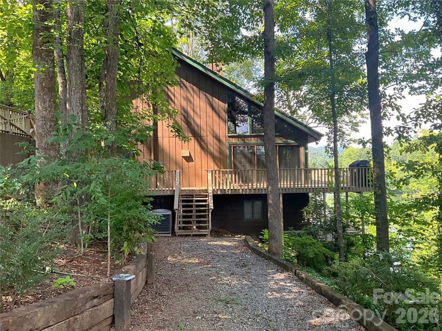 Lake living the way it was meant to be—simple, peaceful, and connected to nature. This is the kind of place you come to unplug from the busyness of the world and settle into a slower pace—where mornings start with coffee on the deck, days are spent on the water, and evenings end under the mountain sky.

Located inside the gates of Rumbling Bald on Lake Lure, this home offers a rare combination—the closest single-family home on West Lake Drive to the amenities, while also featuring both waterfront living and long-range mountain views—so you don’t have to choose between nature and convenience.

Set on Bald Mountain Lake with your own private dock and direct access to the non-motorized lake, you can step outside and immediately enjoy kayaking, paddleboarding, fishing, or simply the quiet of the water. Just as rare, you’re also within walking distance to the private beach on Lake Lure, giving you the best of both worlds—peaceful lake living with access to the main lake experience.

The convenience here is unmatched—enjoy easy access to golf, dining, the Wellness Center, and amenities for all ages, just a short walk or golf-cart ride away, while still feeling tucked away in a private, natural setting.

Inside, the home is warm, inviting, and designed for easy living. The main level offers a comfortable living and dining space, primary suite, full bath, and a wraparound deck that brings the outdoors in. Upstairs, two guest bedrooms, a full bath, and a cozy sitting area provide space to relax and unwind. The lower level is all about gathering—featuring an entertainment area, half bath, and direct access to the lake and dock.

With timeless character and a subtle mid-century modern feel, this home captures the essence of a classic mountain lake retreat—where time slows down, nature takes the lead, and making memories comes easy.

Whether you’re looking for a personal escape, full-time home, or income-producing property, this is a rare opportunity to own a piece of lake life that truly lets you disconnect—without giving up convenience.